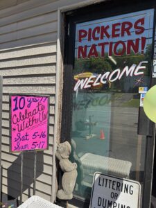Front of Pickers nation store with a bright pink sign that reads "10 years, celebrate with us Sat 5/16 and Sun 5/17"